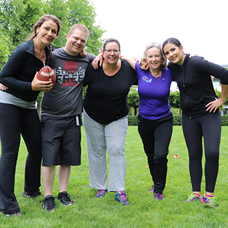 Five people posing with a football